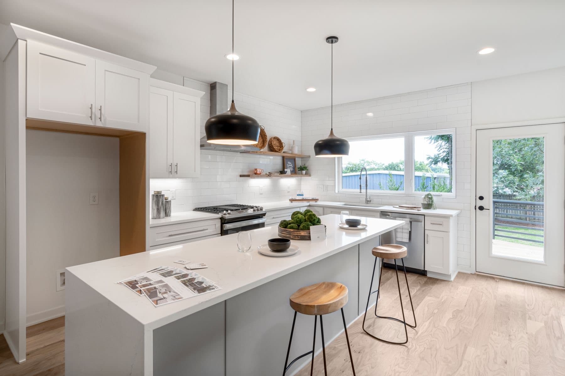 Cuisine claire : îlot, suspensions noires, spots et bandeau sous les meubles. Photographie Pexels, démonstration.